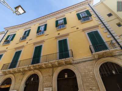 I due livelli sovrastanti presentano una serie di portafinestre con persiane verdi, modanature e timpani lineari, disposte in asse con i portali